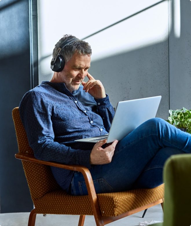 A man wearing headphones while working in his New Jersey offices practices good hearing loss prevention.