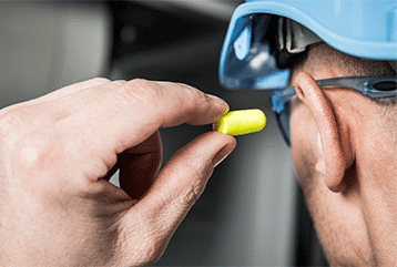 A construction worker putting on hearing protection ear plugs in New Jersey. 